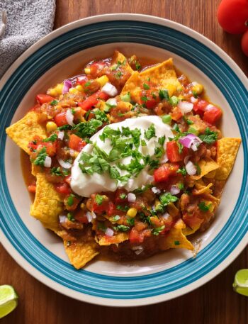 A plate of chilaquiles topped with crumbled cheese, fresh cilantro, and a fried egg.