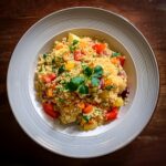 Fluffy couscous served with colorful vegetables and fresh herbs.