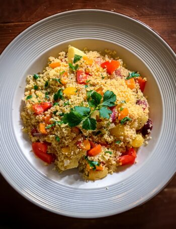 Fluffy couscous served with colorful vegetables and fresh herbs.