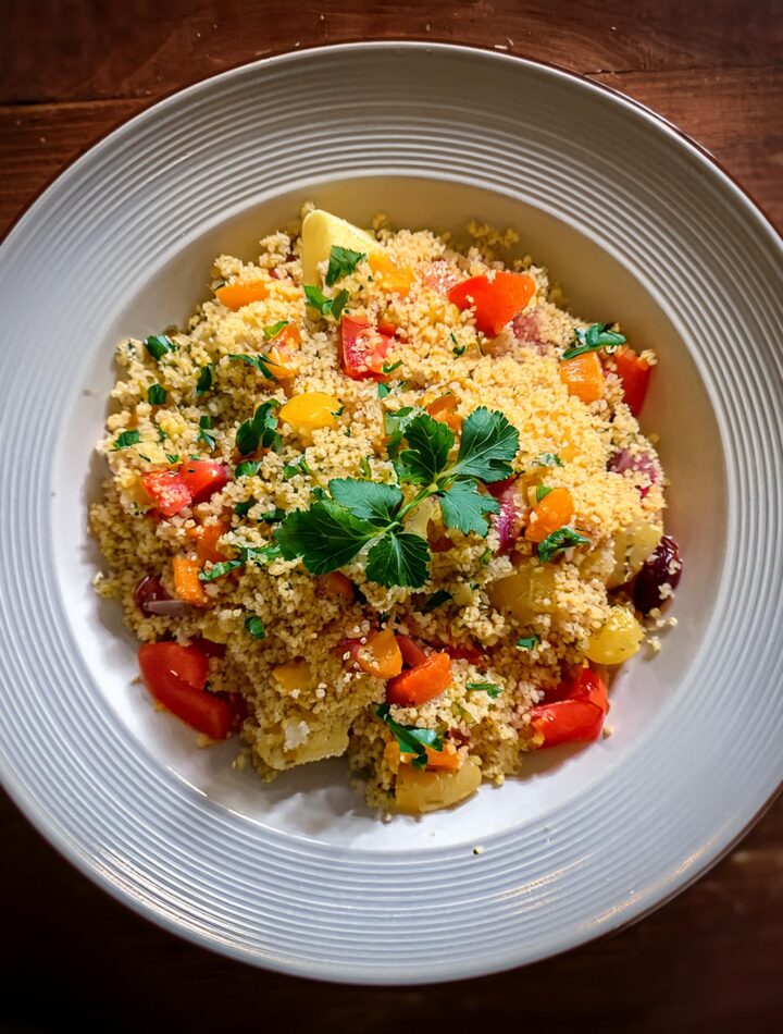 Fluffy couscous served with colorful vegetables and fresh herbs.