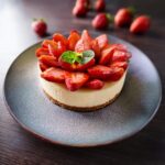 A layered strawberry cheesecake cake with fresh strawberries and creamy frosting