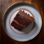 A rich slice of the ultimate chocolate cake topped with creamy frosting and chocolate shavings.