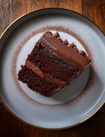 A rich slice of the ultimate chocolate cake topped with creamy frosting and chocolate shavings.