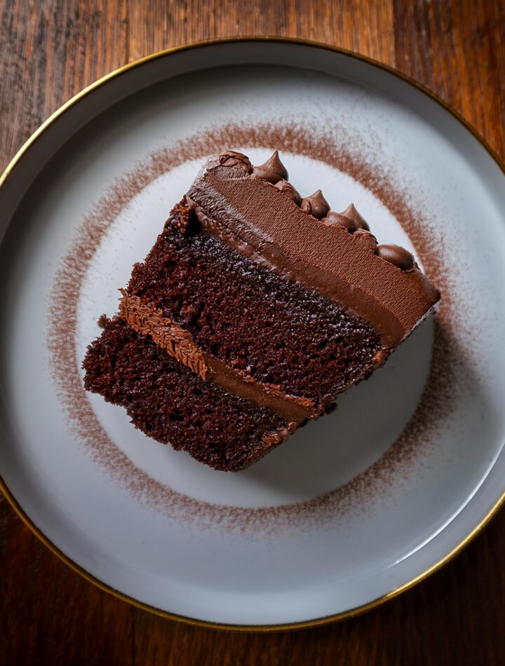 A rich slice of the ultimate chocolate cake topped with creamy frosting and chocolate shavings.